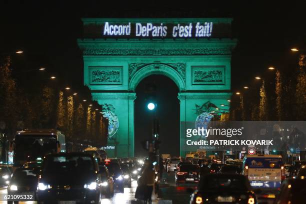 The Arc de Triomphe is illuminated with the lettering reading 'The Paris accord is done' in Paris on November 4 to celebrate the first day of the...