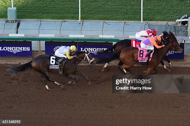 Jockey Gary Stevens aboard Beholder races alongside jockey Mike Smith aboard Songbird to the finish line in the Longines Breeders' Cup Distaff during...