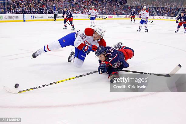 Jeff Petry of the Montreal Canadiens and Josh Anderson of the Columbus Blue Jackets lose their footing while battling for control of the puck during...