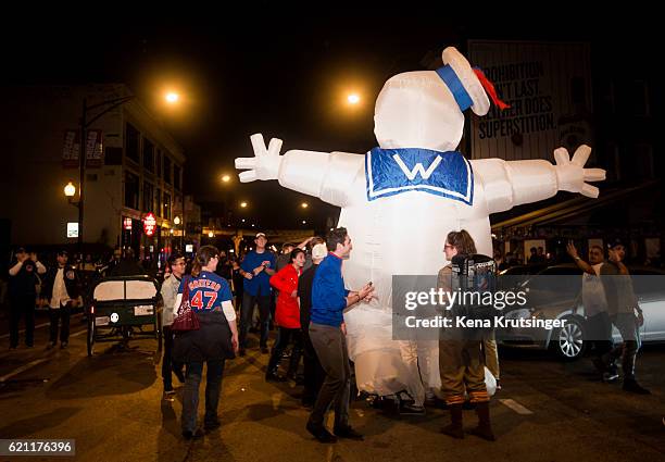 The Ghostbusters "Stay Puft Marshmallow Man" walks the streets while Chicago Cubs fans celebrate outside Wrigley Field after the Cubs defeated the...