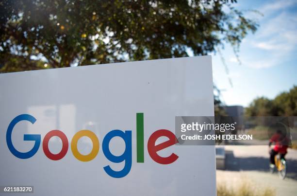 Man rides a bike passed a Google sign and logo at the Googleplex in Mountain View, California on November 4, 2016.