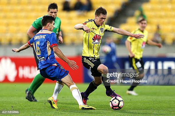 Michael McGlinchey of the Phoenix beats the challenge of Steven Ugarkovic of the Jets during the round five A-League match between the Wellington...