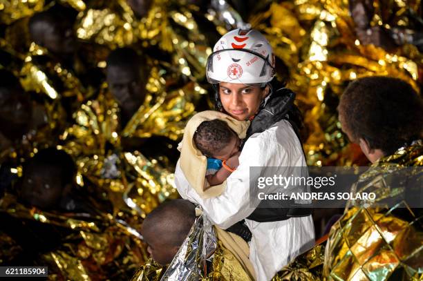 Doctor holds a baby during a rescue operation of migrants and refugees by the crew of the Topaz Responder, a rescue ship run by Maltese NGO "Moas"...