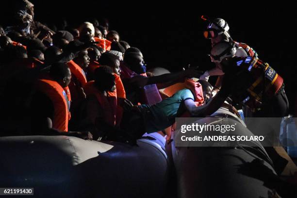 Members of the Maltese NGO MOAS helps a man to board a small rescue boat during a rescue operation of 146 migrants and refugees by the Topaz...