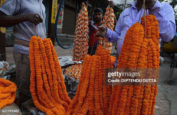 Indian vendors arrange marigold flowers at a roadside stall to be sold ahead of the forthcoming Chhath Puja Festival in Siliguri on on November...