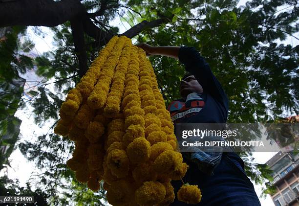 Indian vendors arrange marigold flowers at a roadside stall to be sold ahead of the forthcoming Chhath Puja Festival in Siliguri on on November...