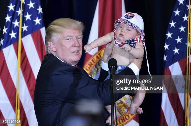 Republican presidential nominee Donald Trump holds a baby during a rally in the Special Events Center of the Florida State Fairgrounds in Tampa,...