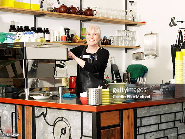 mature female standing by the coffee machine smiling - melbourne cafe stock-fotos und bilder