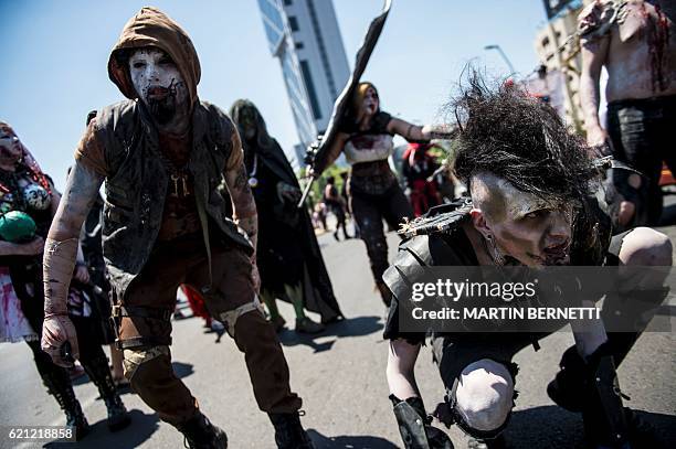 Youngsters fancy dressed and with makeup take part in a "zombie walk" along Alameda Avenue in downrown Santiago, on November 5, 2016. / AFP / Martin...