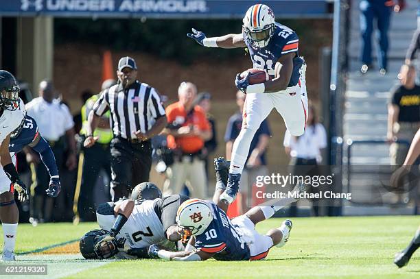 Running back Kerryon Johnson of the Auburn Tigers leaps over wide receiver Stanton Truitt of the Auburn Tigers and safety Arnold Tarpley of the...
