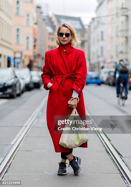 Alice Schimmelpenninck wearing a long red coat with belt, a gym bag, black Nike sneaker, sunglasses on November 5, 2016 in Berlin, Germany.