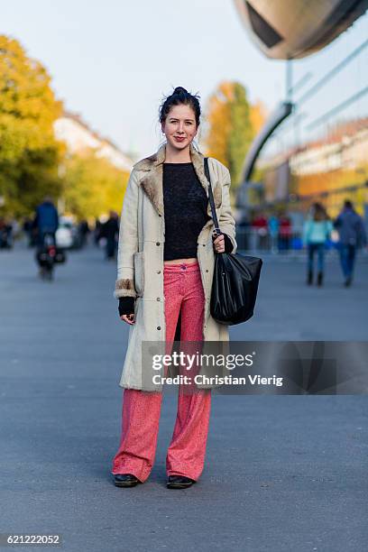 Sophia Engelhardt with a bun wearing a vintage coat with inner lining fur, black bag, wide leg red pants, black cropped longshirt, black leather...