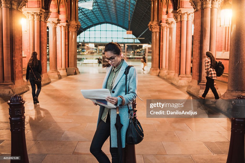 Young businesswoman reading newspaper on the station