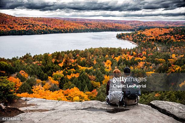 young couple hiking in mountain and relaxing looking at view - travel and canada and fall stockfoto's en -beelden