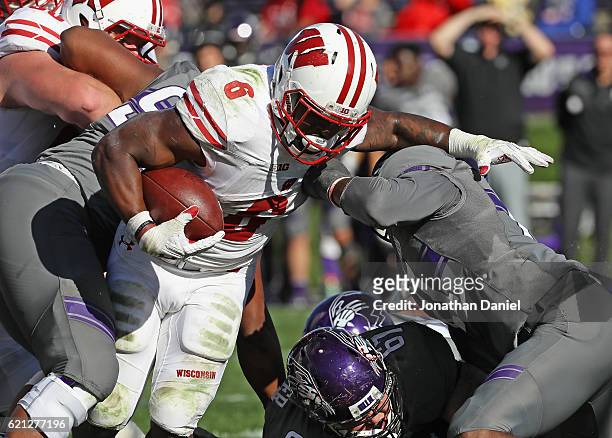 Corey Clement of the Wisconsin Badgers rushes over Tyler Lancaster and Kyle Queiro of the Northwestern Wildcats to score a touchdown in the 4th...