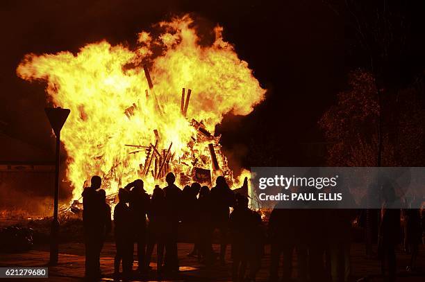 People stand around a large bonfire in Liverpool, north west England, on November 5, 2016. People around Britain light bonfires and burn an effigy,...