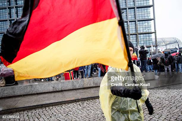 Right-wing activist holds the German National flag as he and others gather in front of Hauptbahnhof main railway station before marching through the...