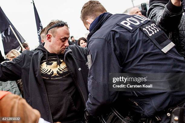 Policeman checks the pockets of new arrivals as right-wing activists gather in front of Hauptbahnhof main railway station before marching through the...