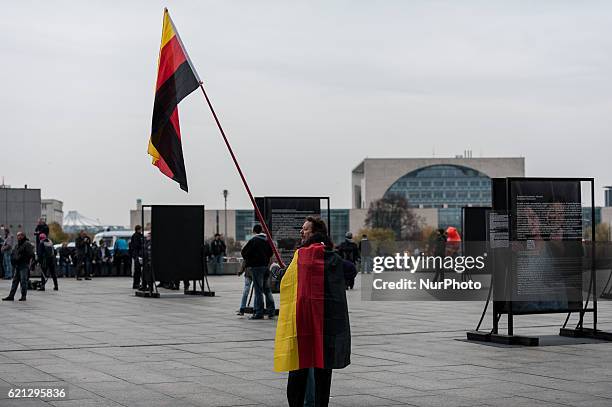 Right-wing activist holds the German National flag as he and others gather in front of Hauptbahnhof main railway station before marching through the...