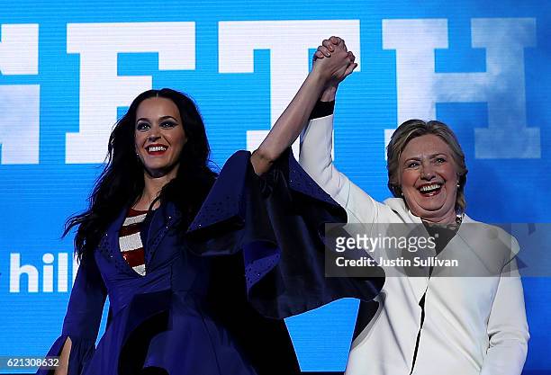 Democratic presidential nominee former Secretary of State Hillary Clinton raises her arms with recording artist Katy Perry during a get-out-the-vote...