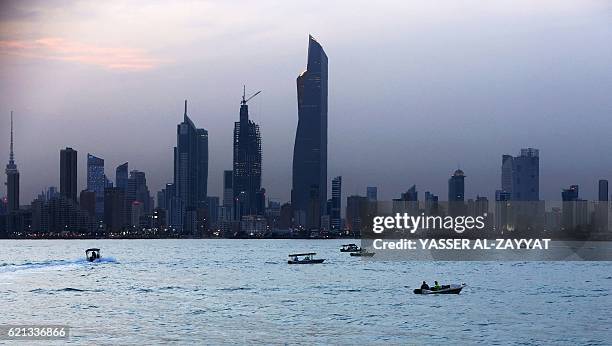 Boats sail in front of Kuwait City's skyline on November 5, 2016. / AFP / Yasser Al-Zayyat