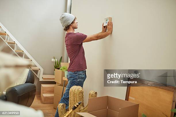 moving home new beginnings. hanging a painting. - hanging photos stock pictures, royalty-free photos & images