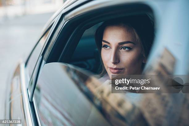 femme sérieuse regardant par la fenêtre d’une voiture - stéréotype de la classe supérieure photos et images de collection