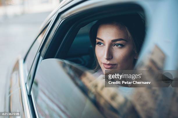 donna seria che guarda fuori dal finestrino di un'auto - luxury foto e immagini stock