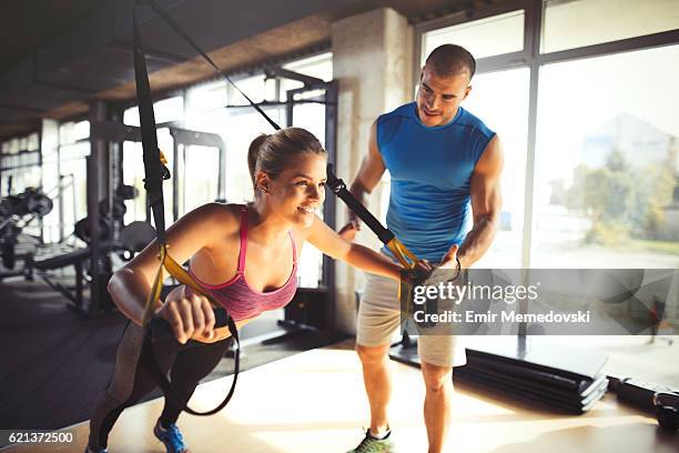 woman doing arm exercises with suspension straps at gym. - suspension training stockfoto's en -beelden