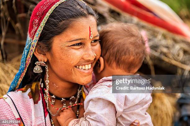 young indian mother holding her little baby, village near jodhpur - childhood poverty stock pictures, royalty-free photos & images