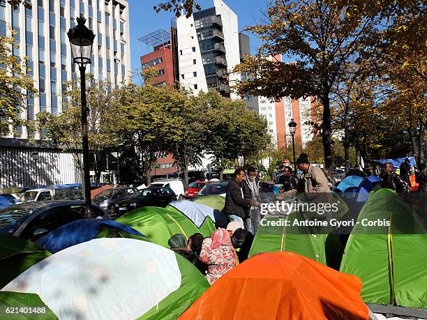 Tents are pitched as migrants stand around near the Stalingrad metro station in a makeshift camp prior to the site being dismantled by authorities on...