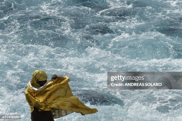 Migrant wrapped in a survival foil blanket stands aboard the Topaz Responder ship, run by Maltese NGO Moas and the Italian Red Cross, while sailing...