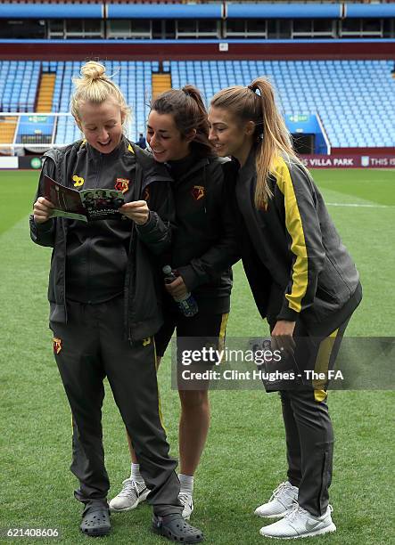 Mollie Burgess, Phoebe Read and Jordan Littleboy of Watford Ladies read a programme on the pitch during the FA WSL 2 match between Aston Villa Ladies...