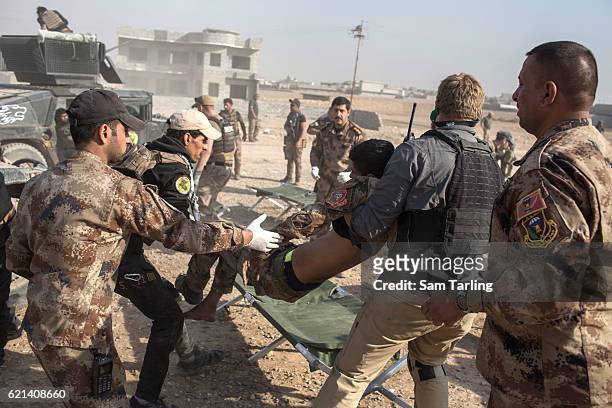 Iraqi Special Forces soldiers aided by volunteers from the Academy of Emergency Medicine help a wounded soldier in the Zahara neighbourhood on the...