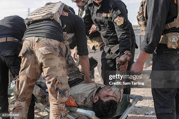 Iraqi Special Forces soldiers aided by volunteers from the Academy of Emergency Medicine help a wounded soldier in the Zahara neighbourhood on the...