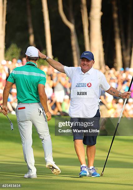 Thorbjorn Olesen of Denmark celebrates victory on the 18th green with caddie Dominic Bott during day four of the Turkish Airlines Open at the Regnum...