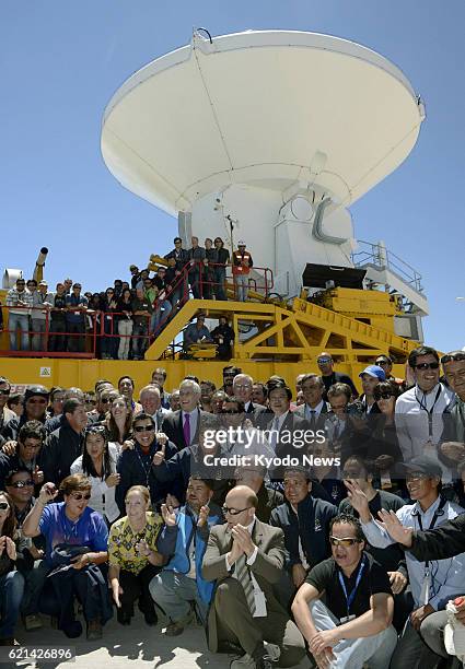 Chile - Researchers and other people concerned pose for photos in front of one of the dish antennas of the Alma telescope, during an opening ceremony...