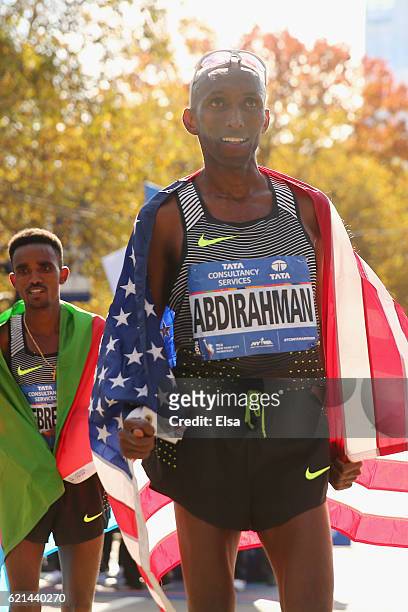 Third-place finisher Abdi Abdirahman of the United States celebrates with the American flag alongside first-place finisher Ghirmay Ghebreslassie of...