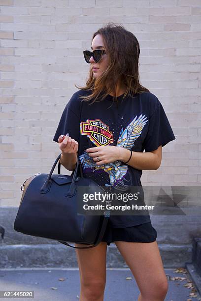 Lily Montasser wearing black oversized vintage cotton Harley-Davidson rock tee with print, large black leather Givenchy duffle bag with carry...