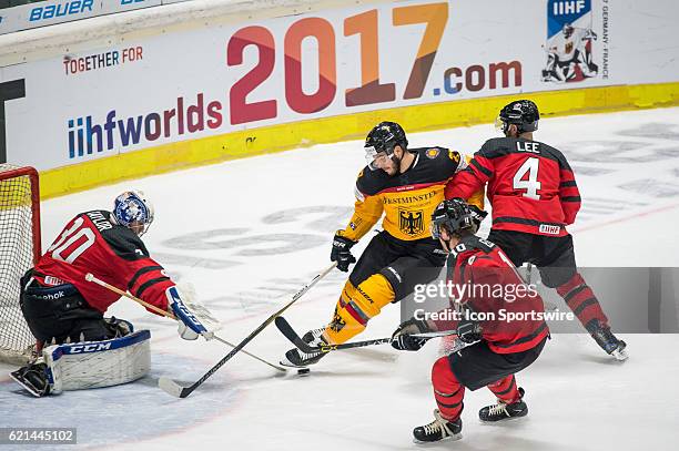 Sebastian Uvira vies with Chris Lee and Goalie Danny Taylor during the Deutschland Cup between Germany and Canada on November 06 at Curt Frenzel...