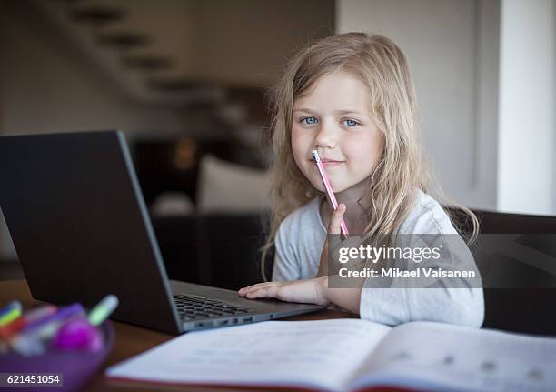 portrait of young girl doing her school work with laptop - children thinking fotografías e imágenes de stock