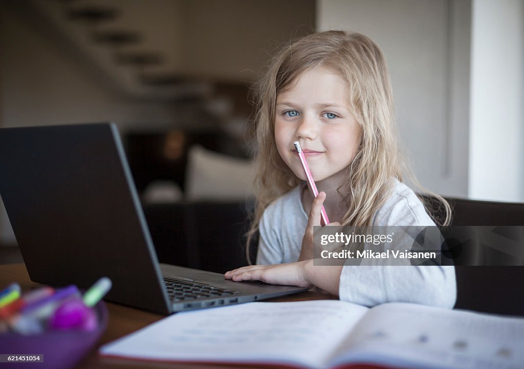 Portrait of young girl doing her school work with laptop