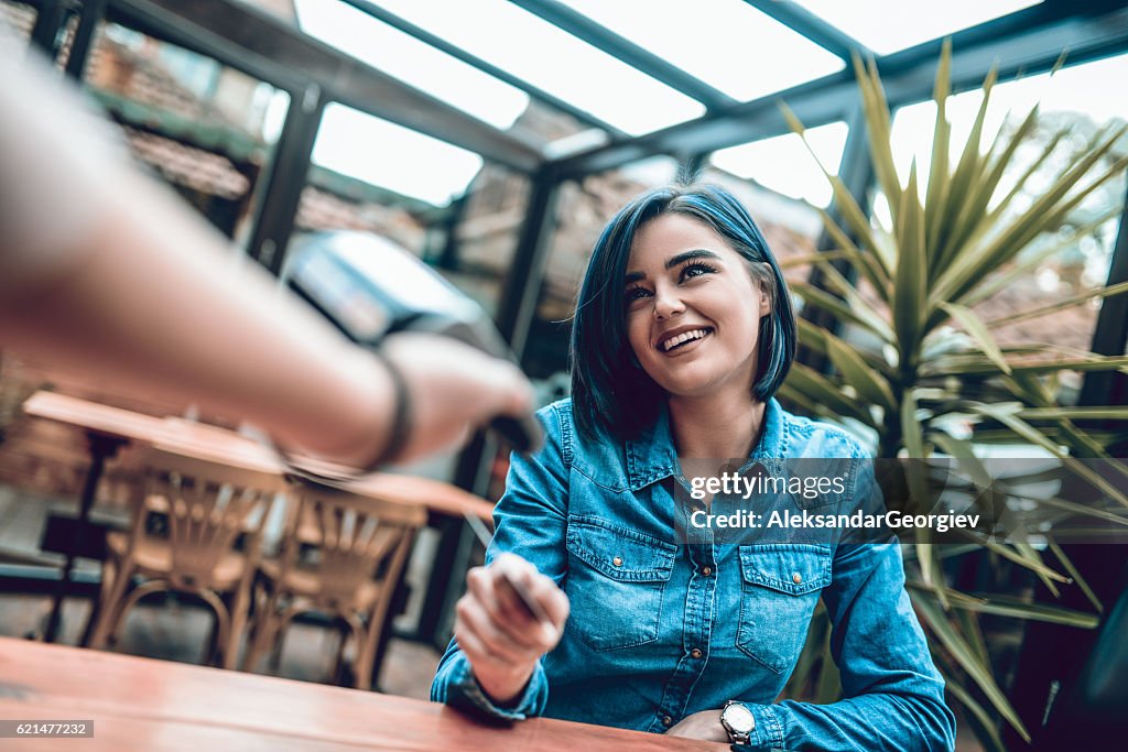 Woman Paying with Credit Card Reader in s Cafe Restaurant