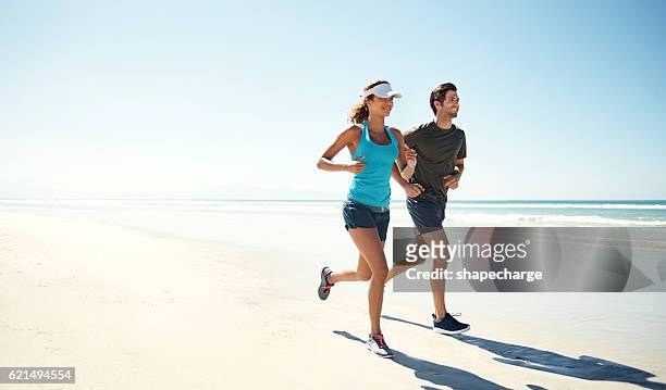training am meer - couple running stock-fotos und bilder