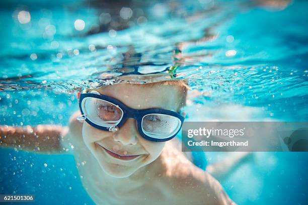 piccolo ragazzo di nuoto sott'acqua in piscina - occhialini da nuoto foto e immagini stock