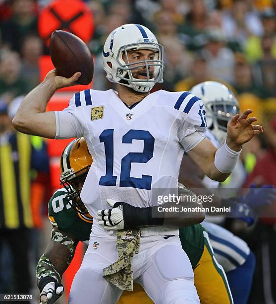 Andrew Luck of the Indianapolis Colts passes as he is hit by Mike Daniels of the Green Bay Packers at Lambeau Field on November 6, 2016 in Green Bay,...