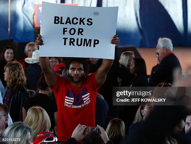 Man hold a "Blacks for Trump" sign as he waits to see US Republican presidential nominee Donald Trump address supporters at Freedom Hill Amphitheater...