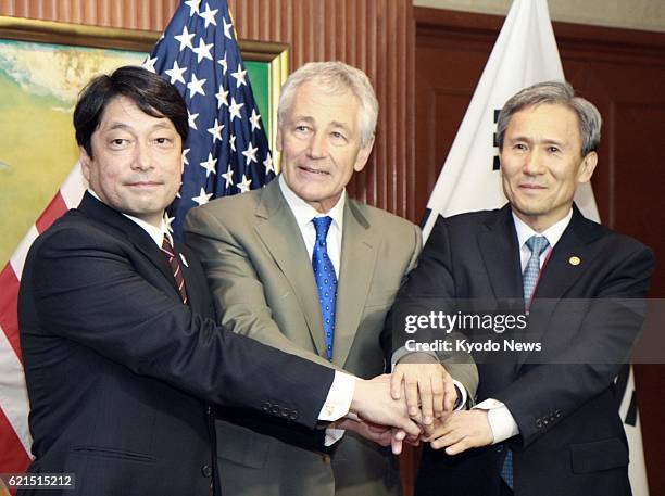 Singapore - Japanese Defense Minister Itsunori Onodera, U.S. Defense Secretary Chuck Hagel and South Korean Defense Minister Kim Kwan Jin join hands...