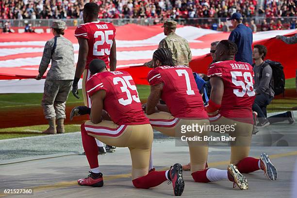 Quarterback Colin Kaepernick, safety Eric Reid, and linebacker Eli Harold of the San Francisco 49ers kneel before a game against the New Orleans...