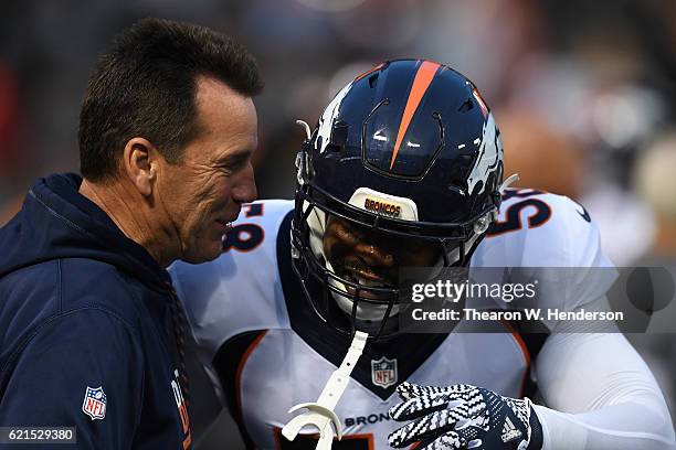 Head coach Gary Kubiak and Von Miller of the Denver Broncos talk on the field prior to the game against Oakland Raiders at Oakland-Alameda County...